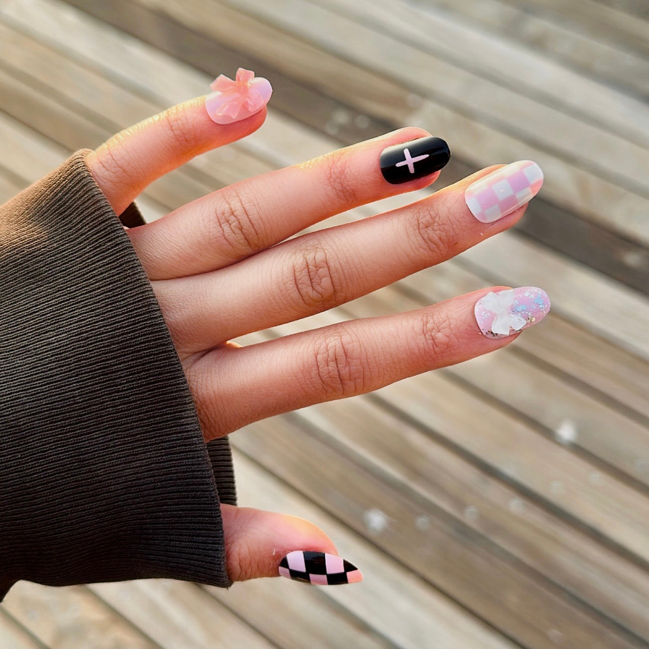 short round long lasting press on nails, pink black and white with multiple designs and bow charms.